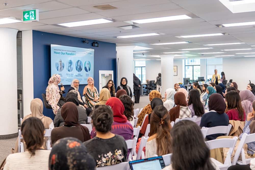 Several women in tech speak in front of an audience of other women