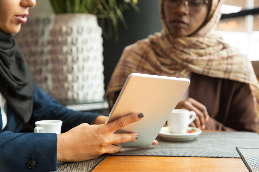 Muslim female colleagues watching content on tablet